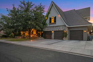View of front of home featuring stone siding, driveway, and stucco siding