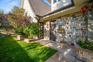 Doorway to property featuring a lawn and stone siding