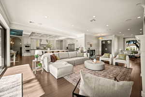 Living area featuring crown molding, a decorative wall, a wainscoted wall, recessed lighting, and dark wood-style flooring