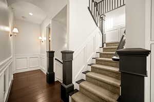 Stairs with a decorative wall, a wainscoted wall, wood-type flooring, and recessed lighting