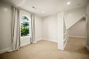 Empty room with light colored carpet and recessed lighting