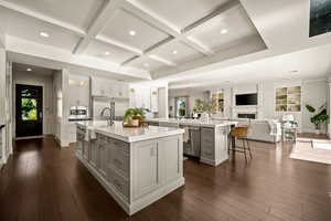 Kitchen featuring coffered ceiling, a kitchen breakfast bar, open floor plan, a peninsula, and recessed lighting