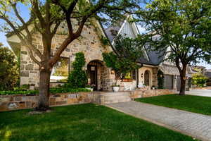 Tudor home with stone siding, a front yard, and a garage