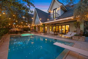 Rear view of property featuring a patio area, stucco siding, a pool with connected hot tub, and a balcony