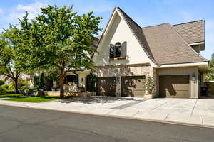 View of front of home featuring concrete driveway, stone siding, stucco siding, and a garage