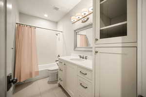 Bathroom with vanity, shower / tub combo with curtain, and light tile patterned flooring