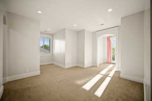 Spare room featuring arched walkways, recessed lighting, and light colored carpet