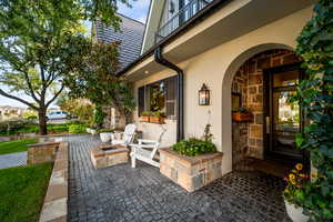 Property entrance with stone siding, stucco siding, and a patio area