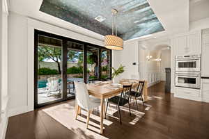 Dining space featuring a tray ceiling, dark wood-style flooring, and arched walkways