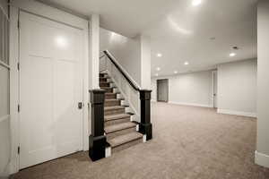 Finished basement with light colored carpet and recessed lighting