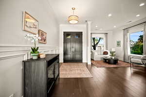 Entryway featuring crown molding, dark wood finished floors, a wainscoted wall, and recessed lighting