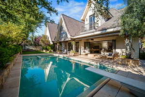 View of swimming pool featuring patio surround, outdoor furniture, a fenced backyard, and a diving board