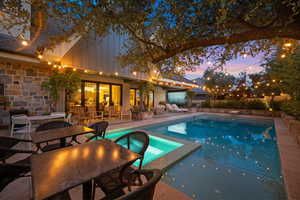 Pool at dusk featuring a patio, a pool with connected hot tub, and outdoor dining space