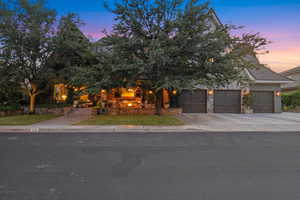 View of property hidden behind natural elements with concrete driveway, a garage, and a lawn