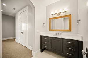 Bathroom with vanity, light carpet, and a closet