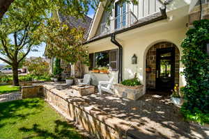 Entrance to property with stone siding, board and batten siding, a patio area, stucco siding, and a lawn