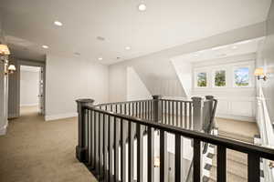 Hallway with light carpet, recessed lighting, and an upstairs landing