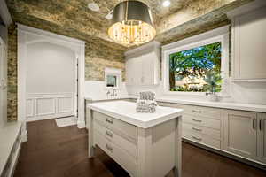 Laundry area featuring wainscoting, suspended lighting, dark wood-style flooring, and wallpapered walls