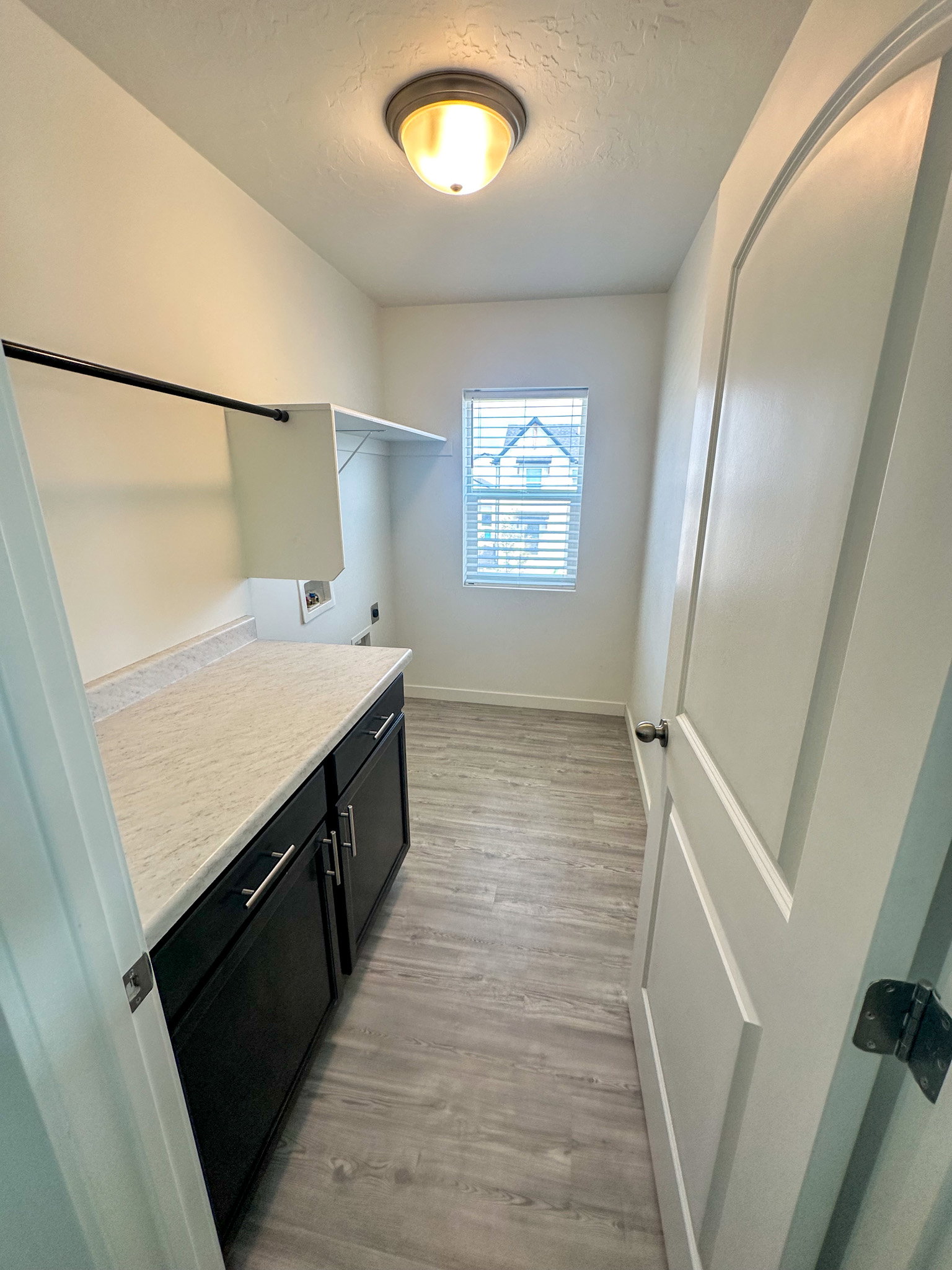 Laundry room with cabinet space, light wood-style floors, electric dryer hookup, a textured ceiling, and washer hookup