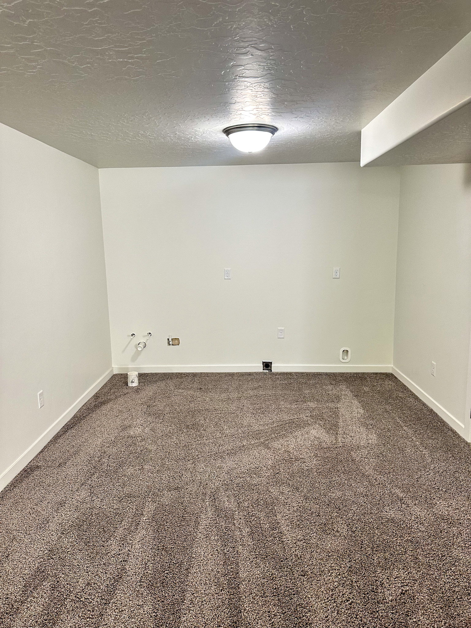 Unfurnished room with a textured ceiling and dark colored carpet