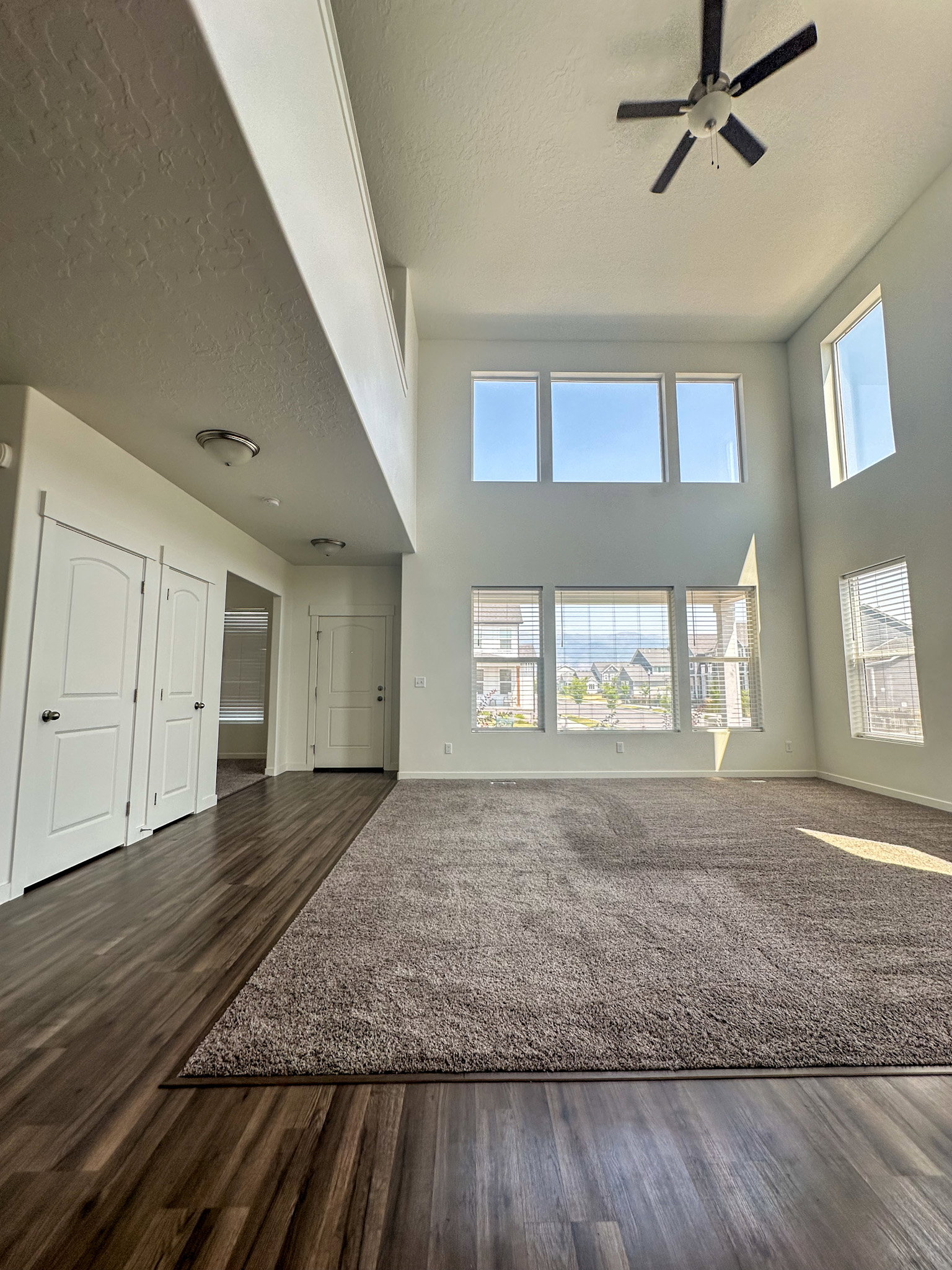 Unfurnished living room with a high textured ceiling, a ceiling fan, and dark wood finished floors