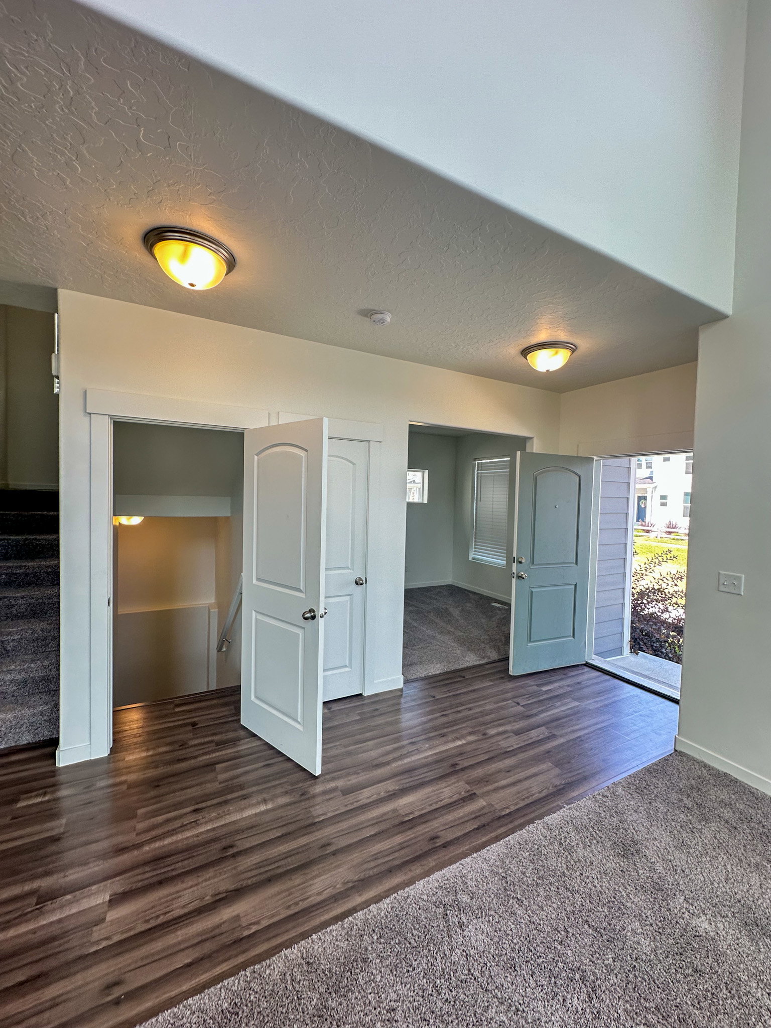 Entryway featuring a textured ceiling, dark wood finished floors, and dark colored carpet