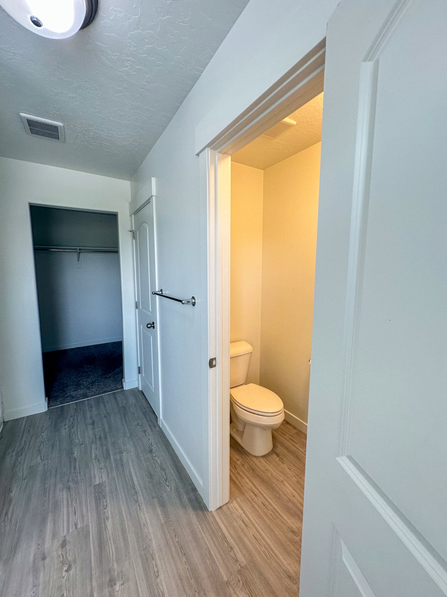 Bathroom featuring light wood finished floors, a textured ceiling, and a spacious closet