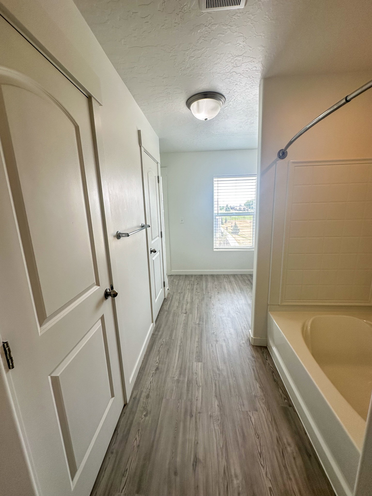 Full bathroom featuring a textured ceiling, dark wood-style floors, and shower / washtub combination