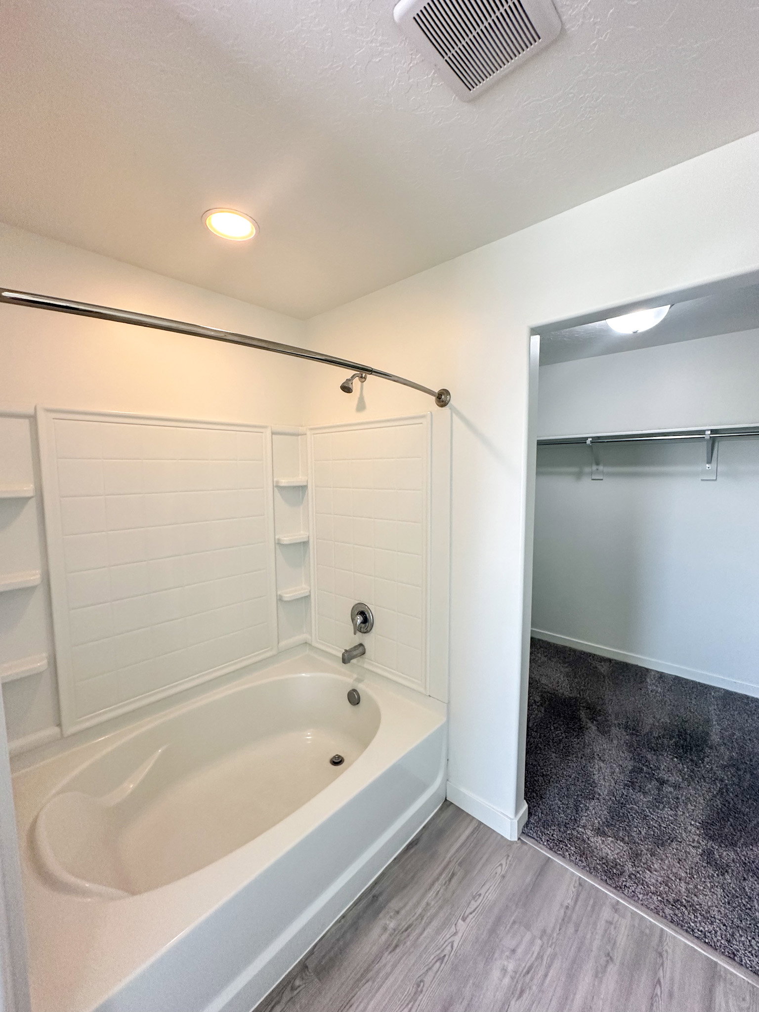 Full bath featuring a spacious closet, shower / tub combination, light wood-style floors, and a textured ceiling