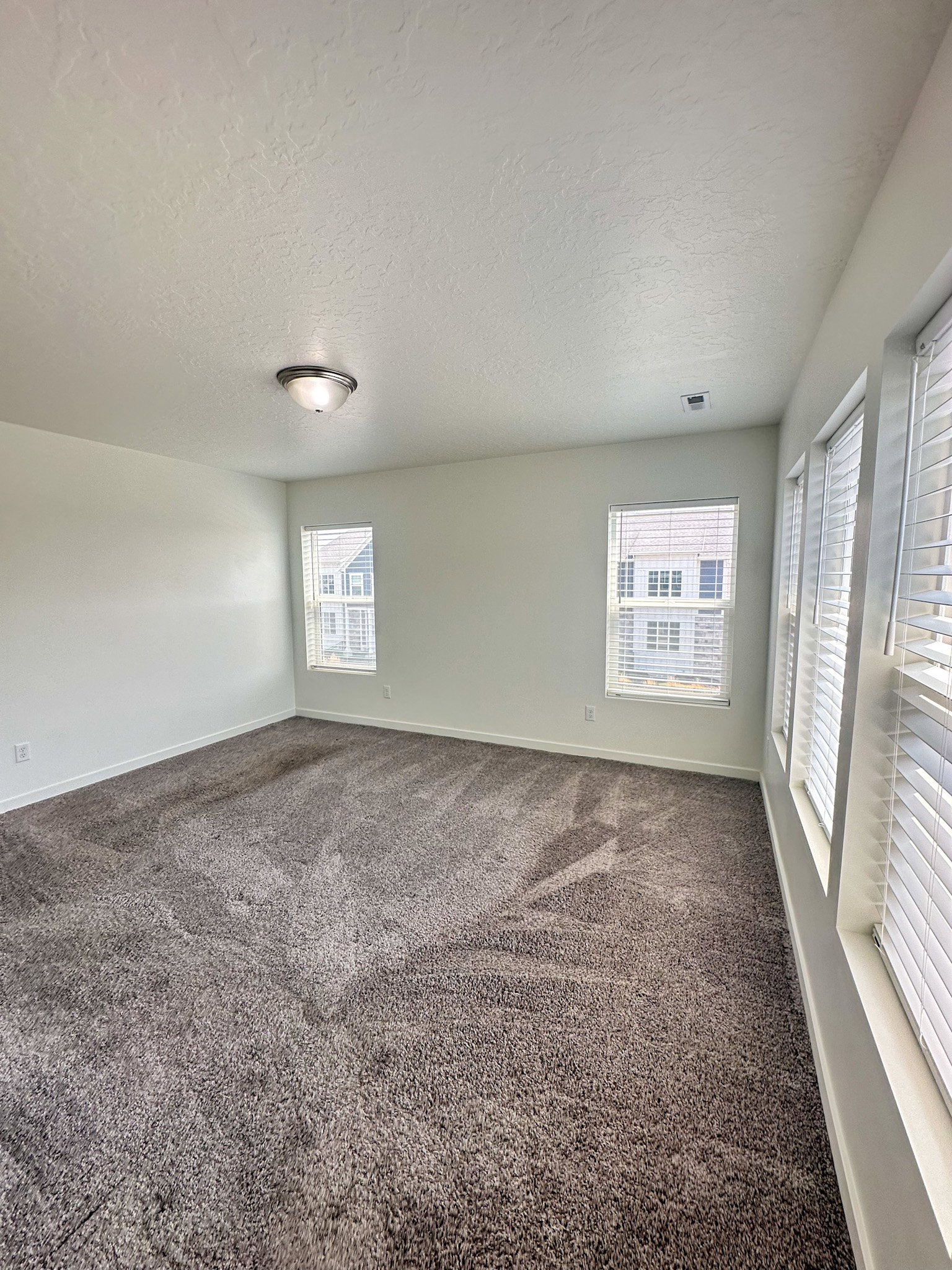 Unfurnished room featuring dark colored carpet and a textured ceiling