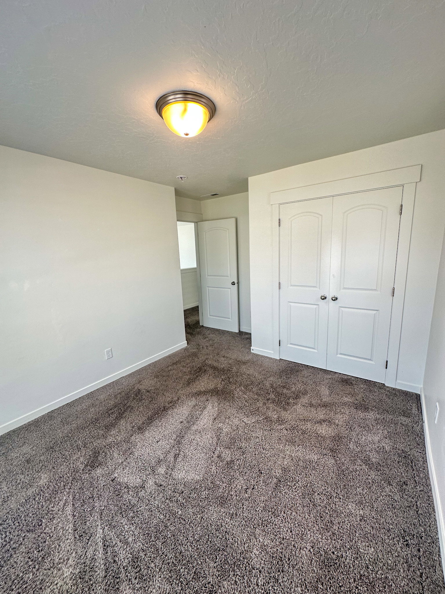 Unfurnished bedroom featuring dark colored carpet, a closet, and a textured ceiling