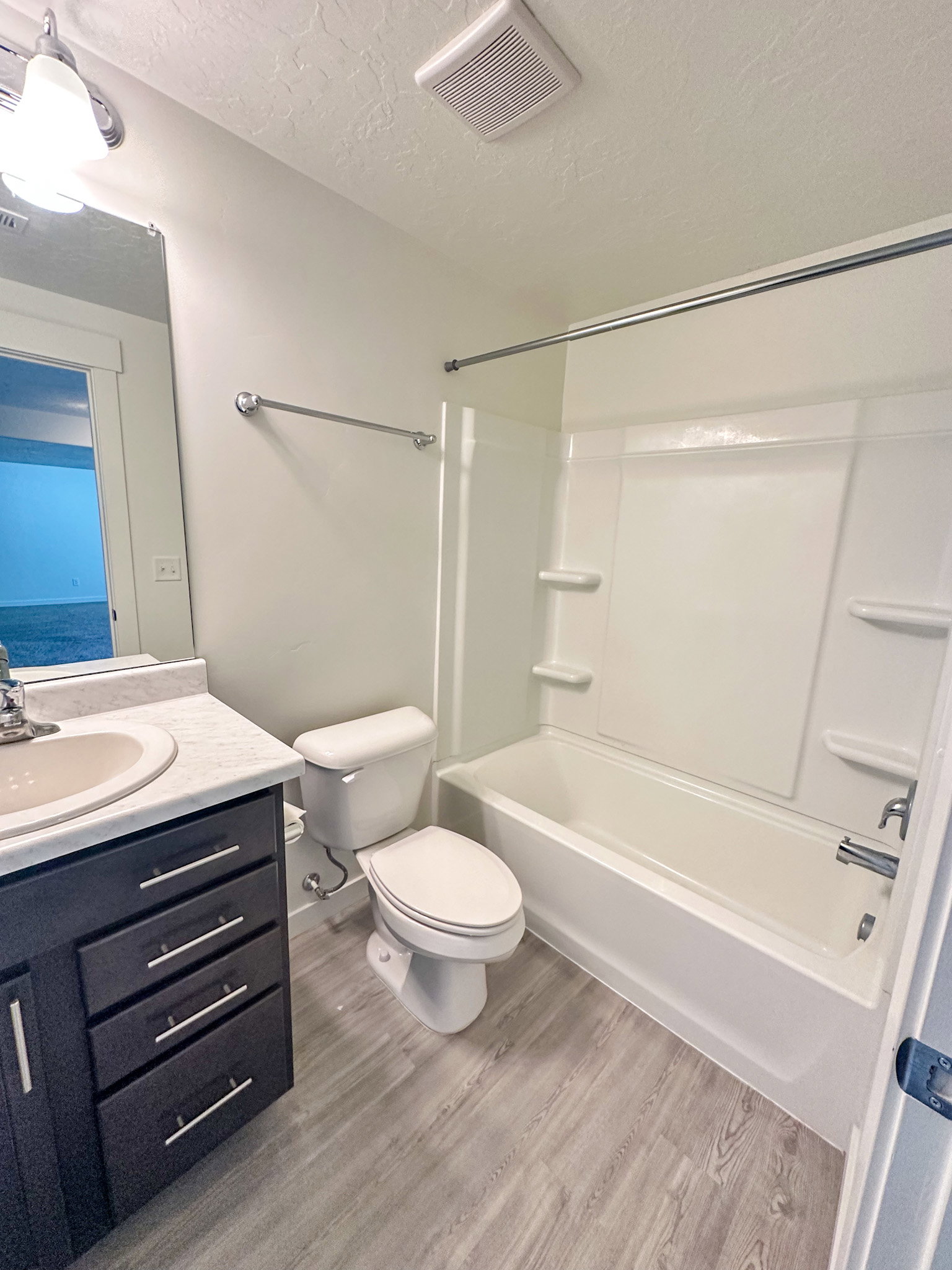 Bathroom featuring vanity, shower / bath combination, light wood finished floors, and a textured ceiling