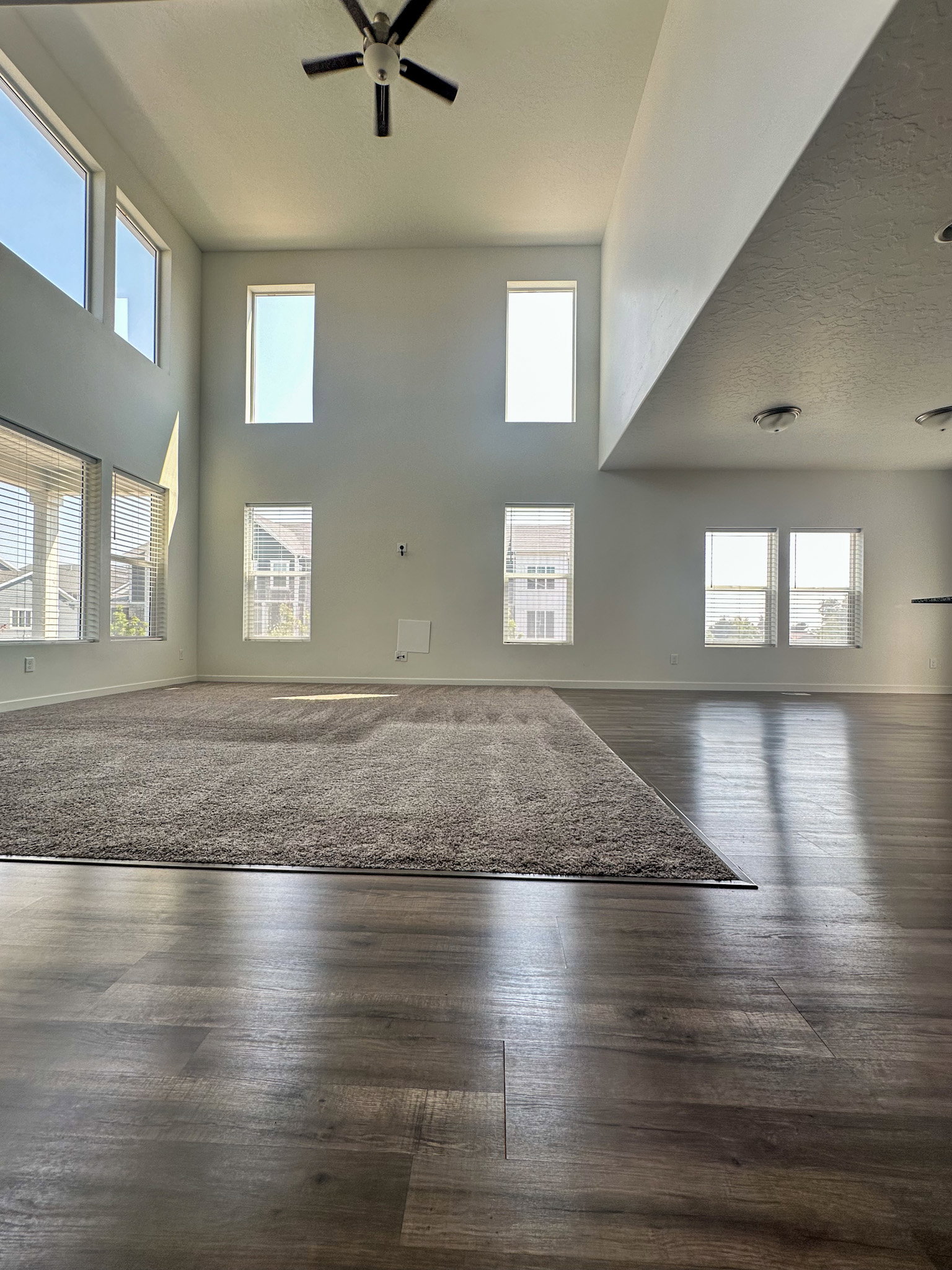 Unfurnished living room featuring ceiling fan, dark wood finished floors, and a high textured ceiling