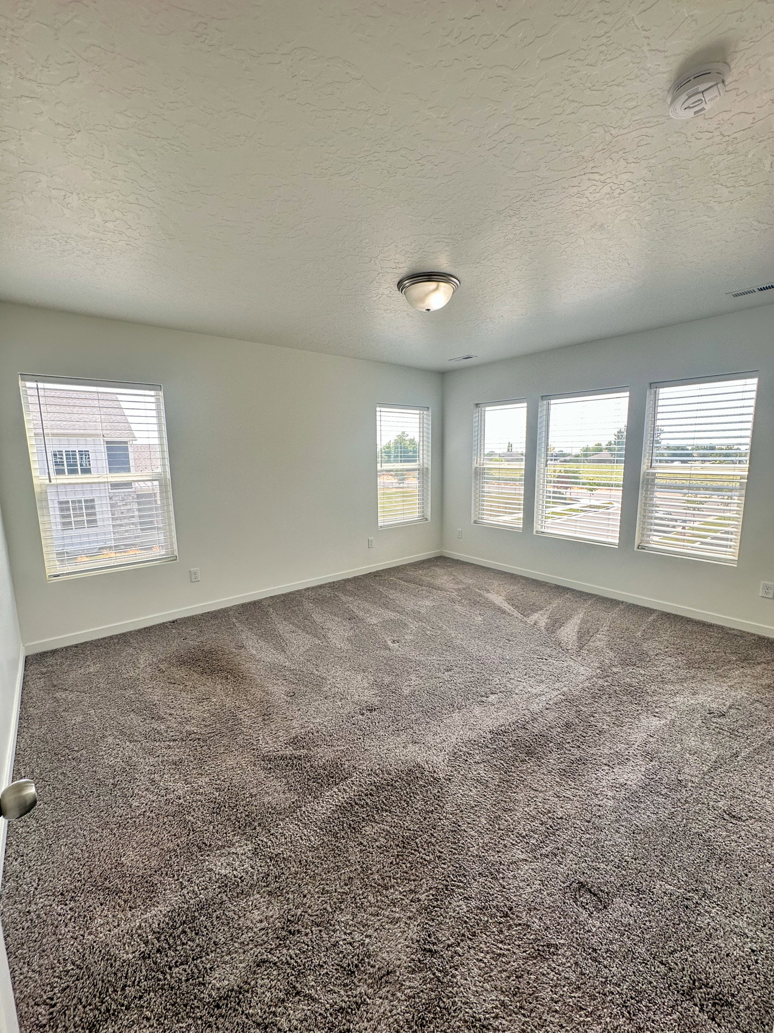 Spare room with a textured ceiling, carpet, and a smoke detector