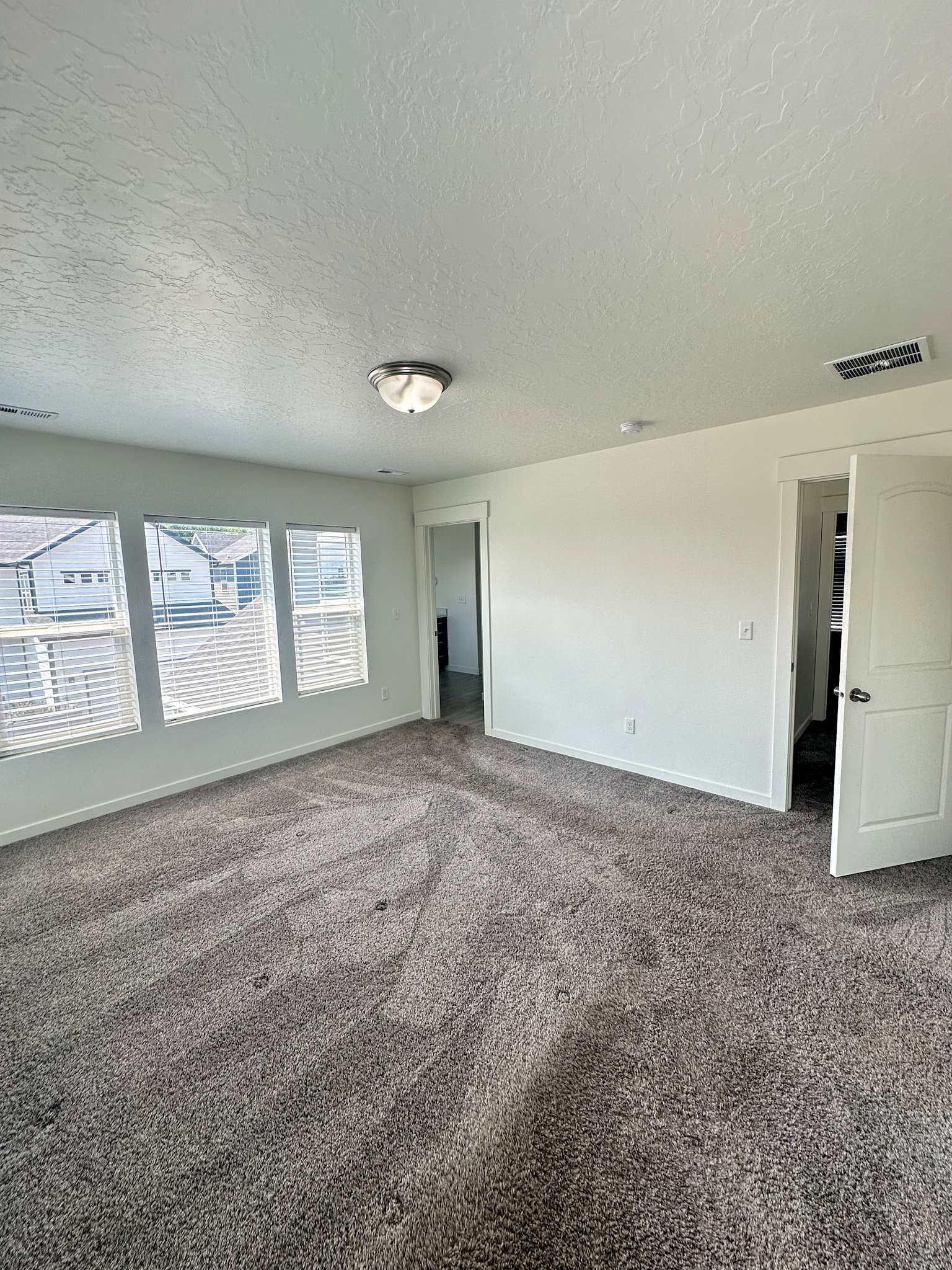 Empty room with dark carpet and a textured ceiling