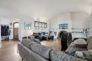 Living room featuring a barrel ceiling, wood finished floors, and a fireplace with raised hearth