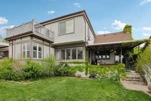 Back of house with stucco siding, a yard, a chimney, and a sunroom