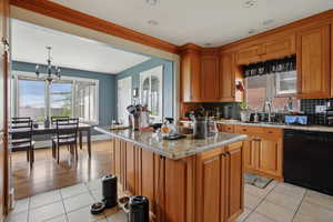 Kitchen with wood finish cabinetry, dishwasher, suspended lighting, backsplash, and ornamental molding