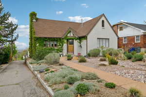 Tudor house with a chimney, a shingled roof, and stucco siding