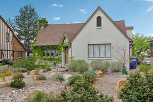 Tudor house with a shingled roof, a chimney, and stucco siding
