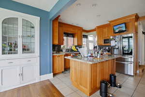 Kitchen featuring stainless steel appliances, light stone countertops, wood finish cabinetry, tasteful backsplash, and a center island