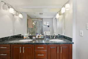 Full bathroom featuring double vanity and a shower stall