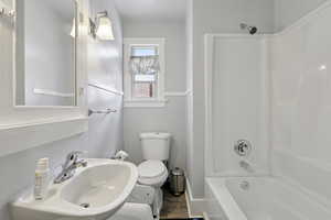 Full bathroom with tub / shower combination and dark wood-style flooring