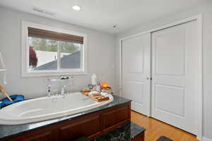 Bathroom featuring a garden tub, light wood-type flooring, and recessed lighting