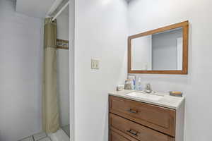 Full bathroom featuring a stall shower, vanity, and light tile patterned floors