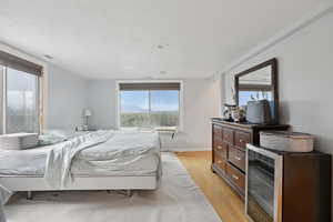 Bedroom featuring light wood-style flooring, multiple windows, and stainless steel fridge