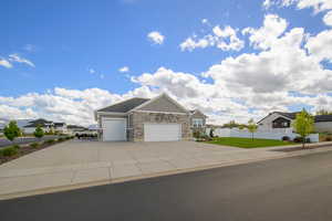 Craftsman-style home featuring a garage, board and batten siding, stone siding, a residential view, and driveway