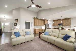 Great room featuring suspended lighting, vaulted ceiling, a ceiling fan, and light wood finished floors