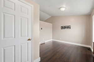 Unfurnished room with lofted ceiling and dark wood finished floors