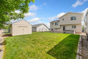 Fenced backyard featuring a hot tub and a storage unit